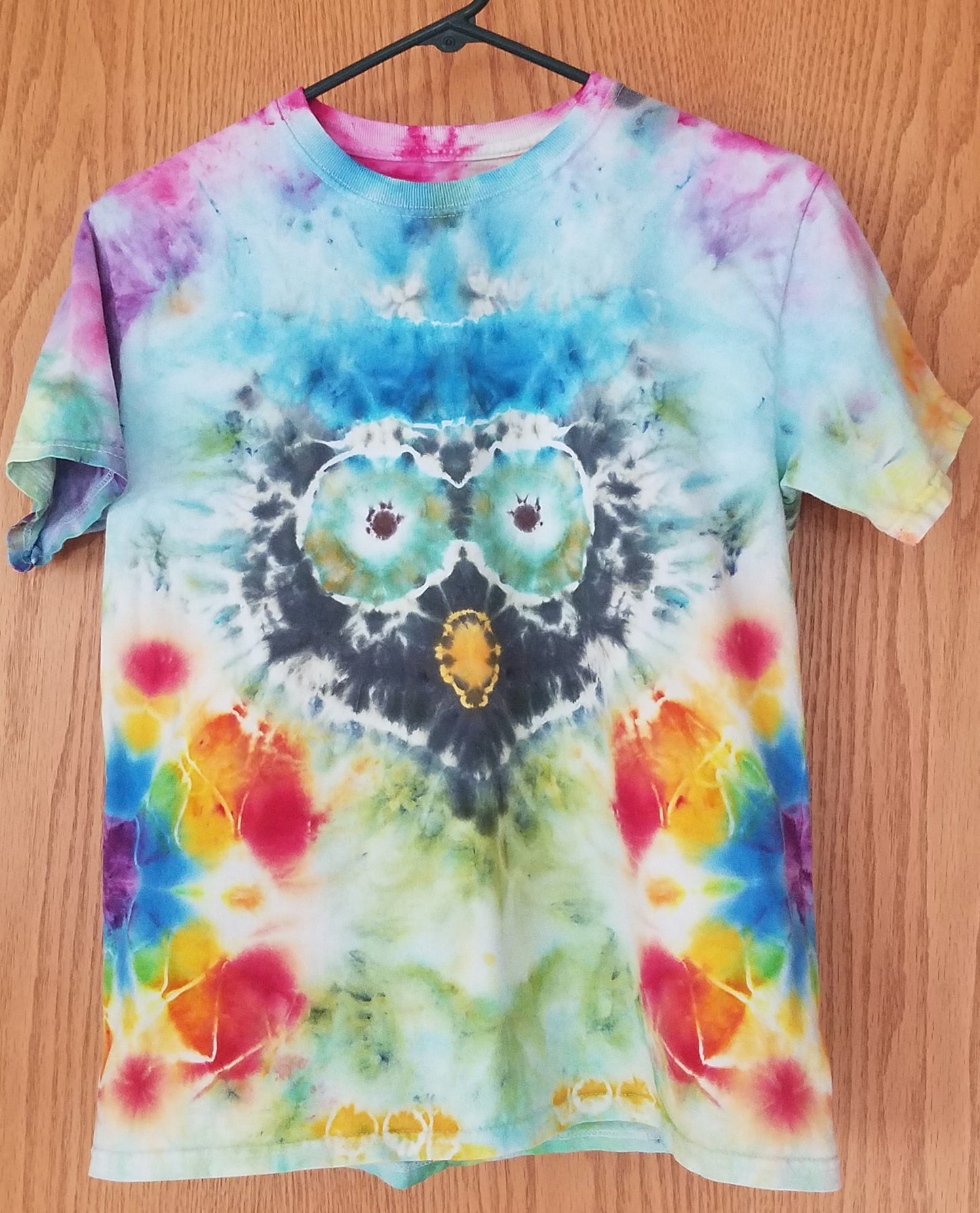 Colorful tie-dye t-shirt with owl design on a wooden surface