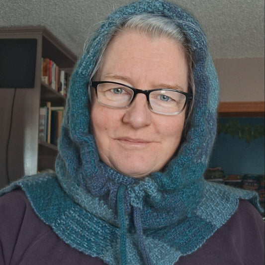 Person wearing a blue woven hood over their head in an indoor setting