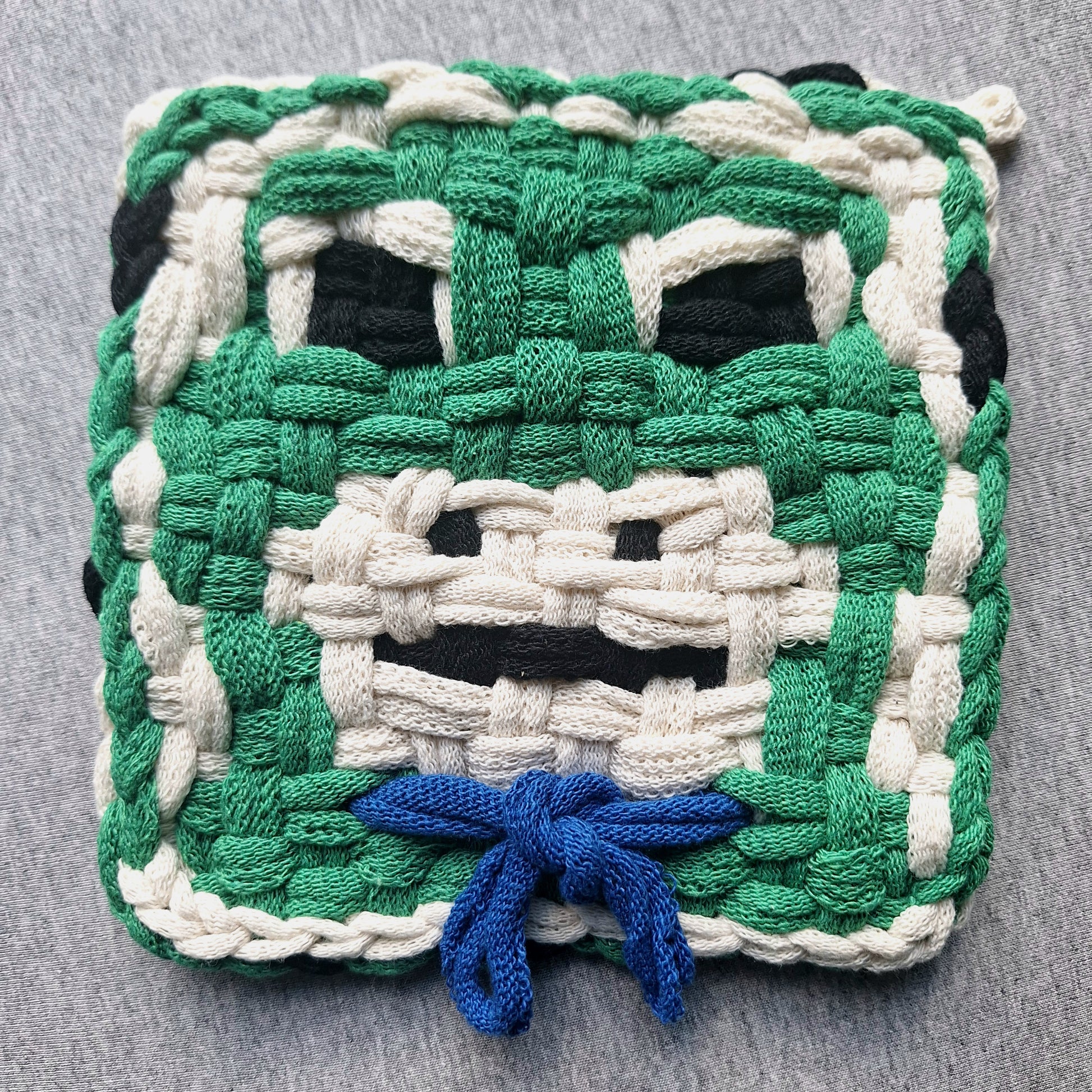 Woven potholder frog with a blue bow