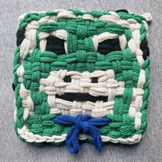 Woven potholder frog with a blue bow