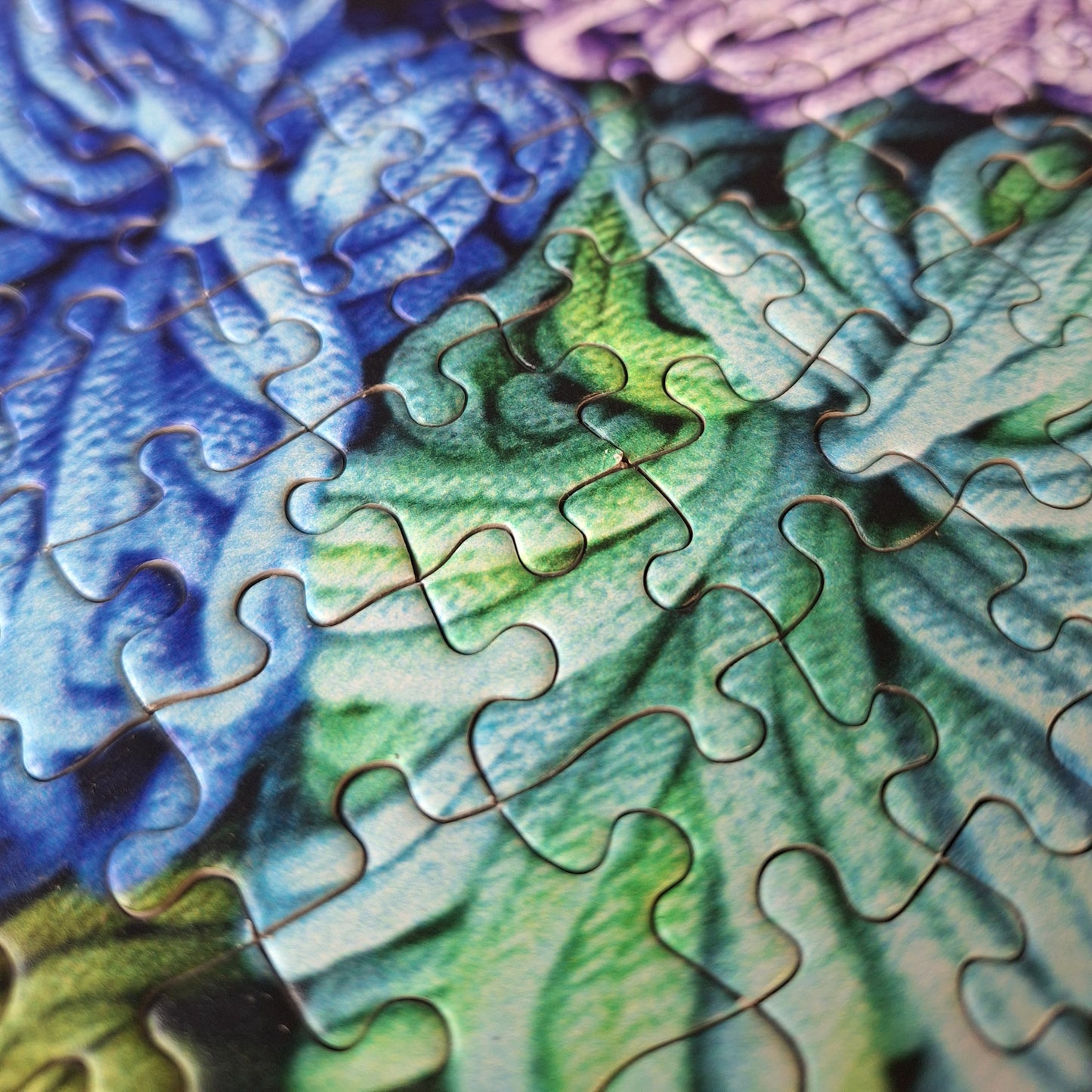 Close-up of a partially completed puzzle with blue, green, and purple pieces.