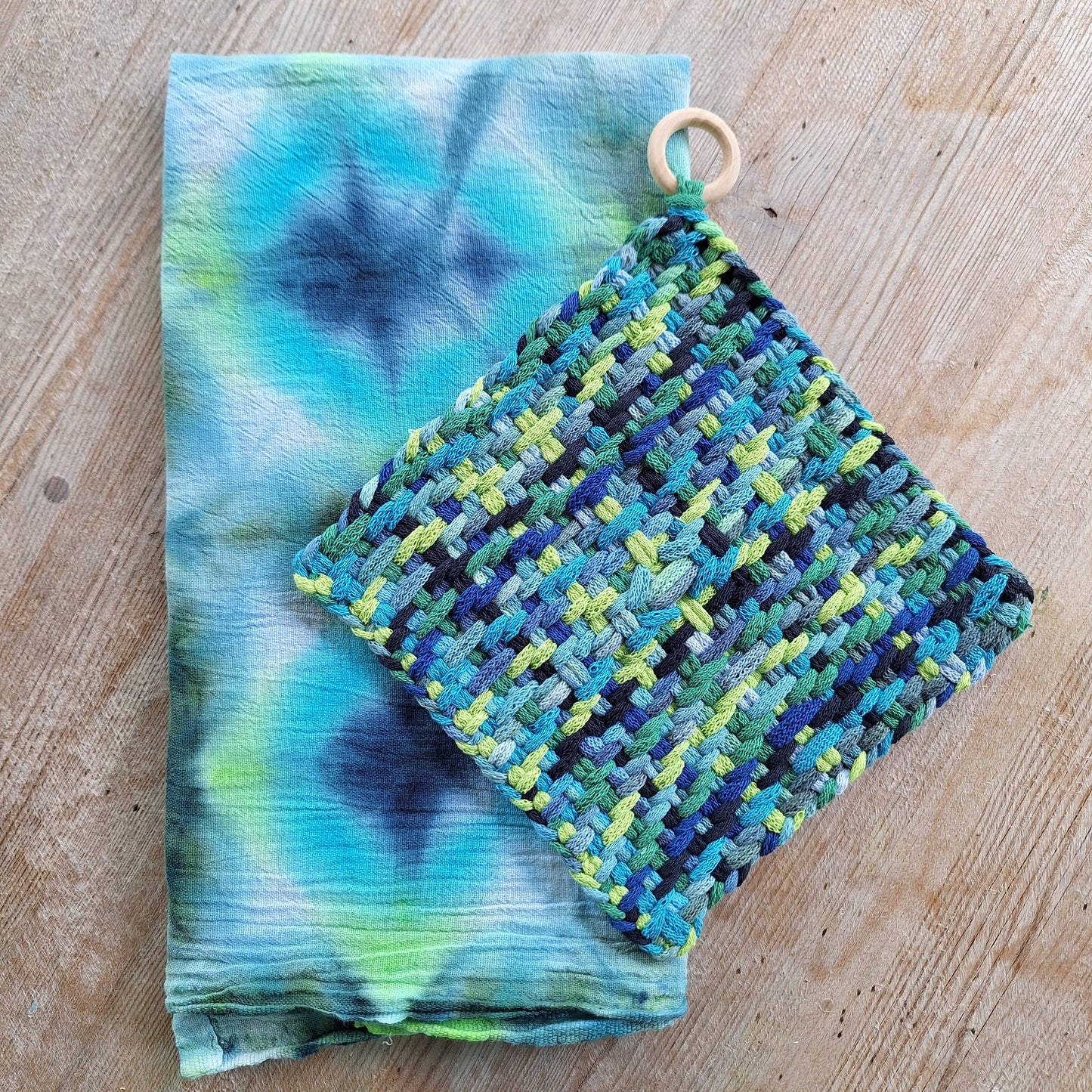 set of a hand dyed dishtowel and a handwoven potholder in shades of blue and green