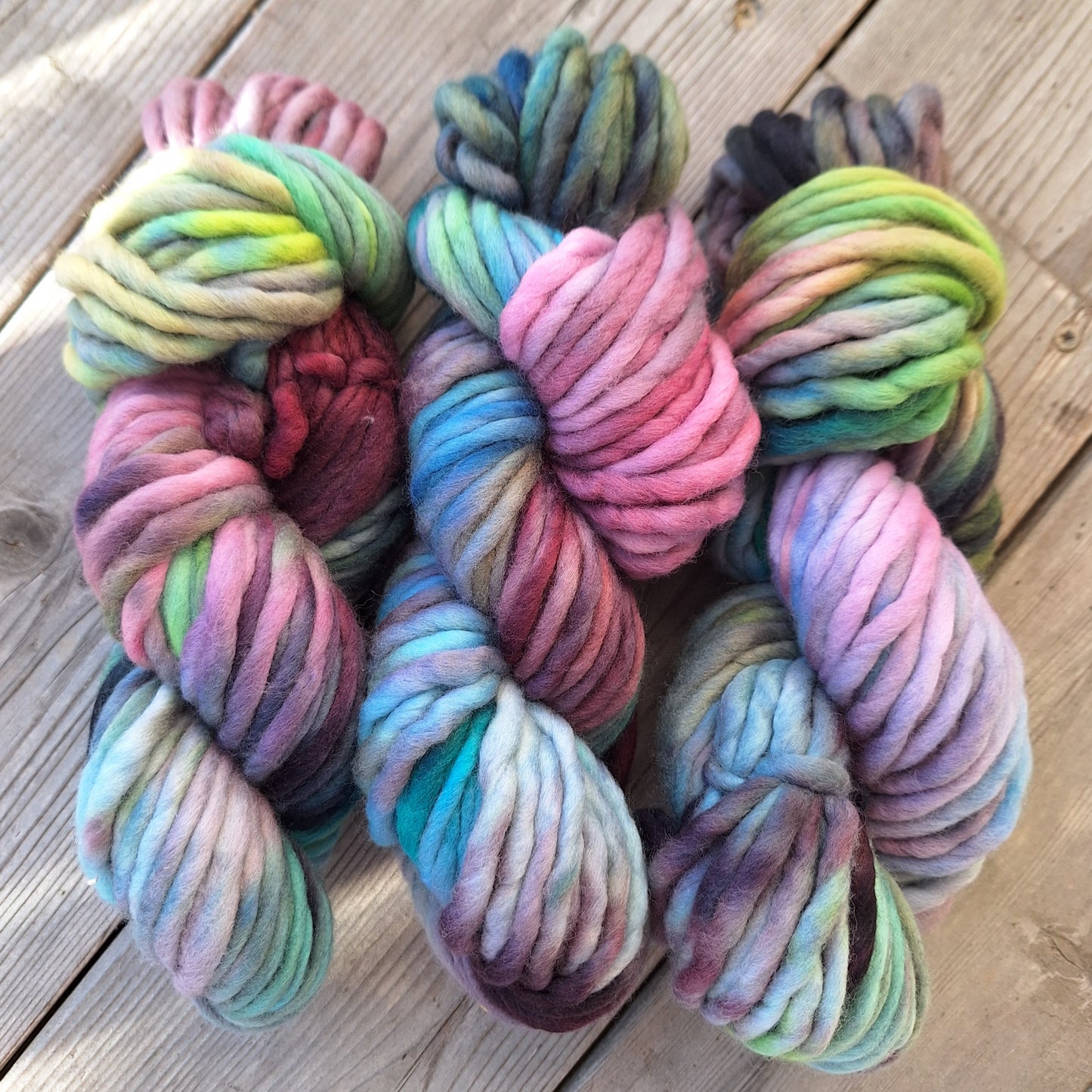 Colorful skeins of pencil roving yarn on a wooden surface