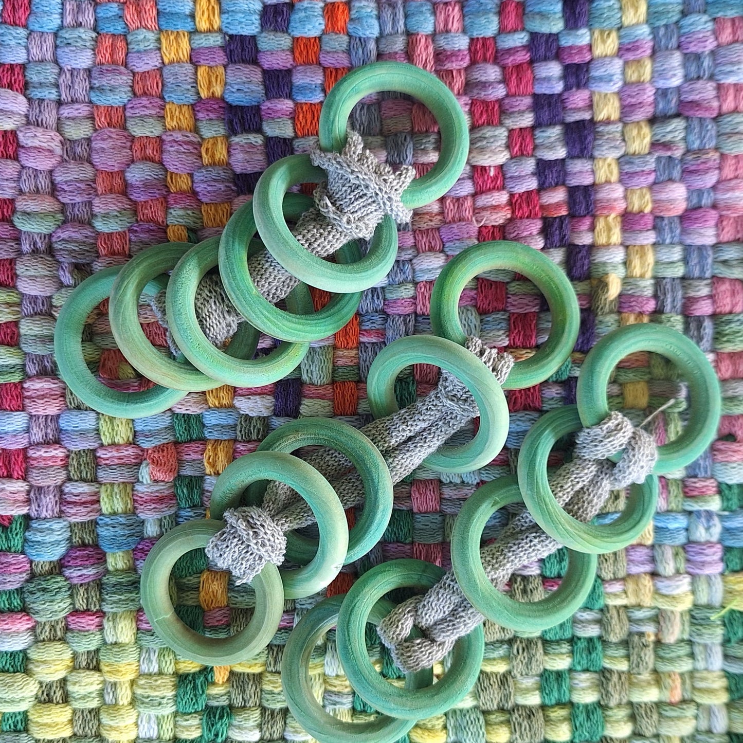 Sets of green hand dyed wooden rings on a woven textile background