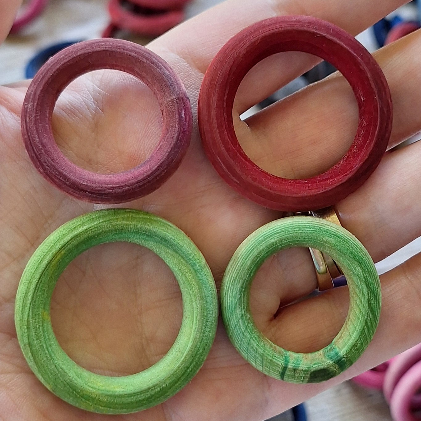 Hand holding colorful hand dyed potholder ring with more rings in the background