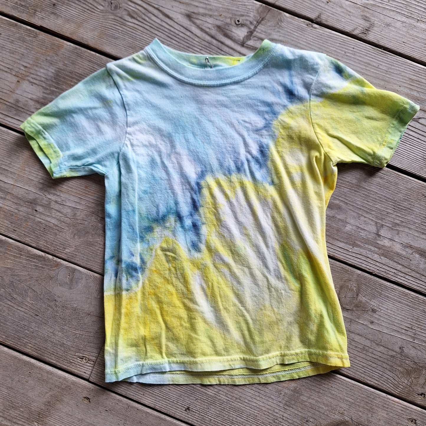 Tie-dye shirt with blue and yellow patterns on a wooden surface