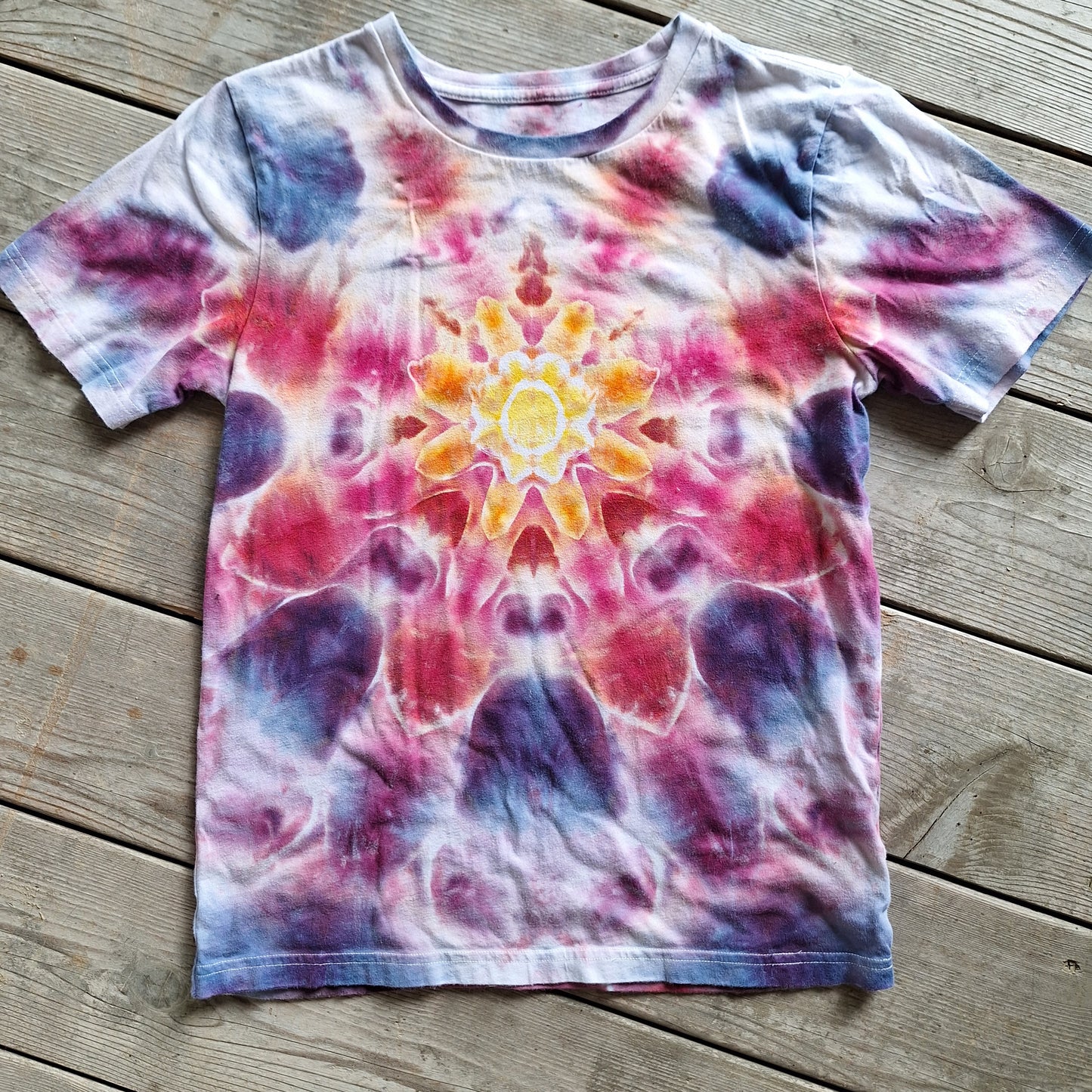 Tie-dye t-shirt with a colorful mandala design on a wooden surface