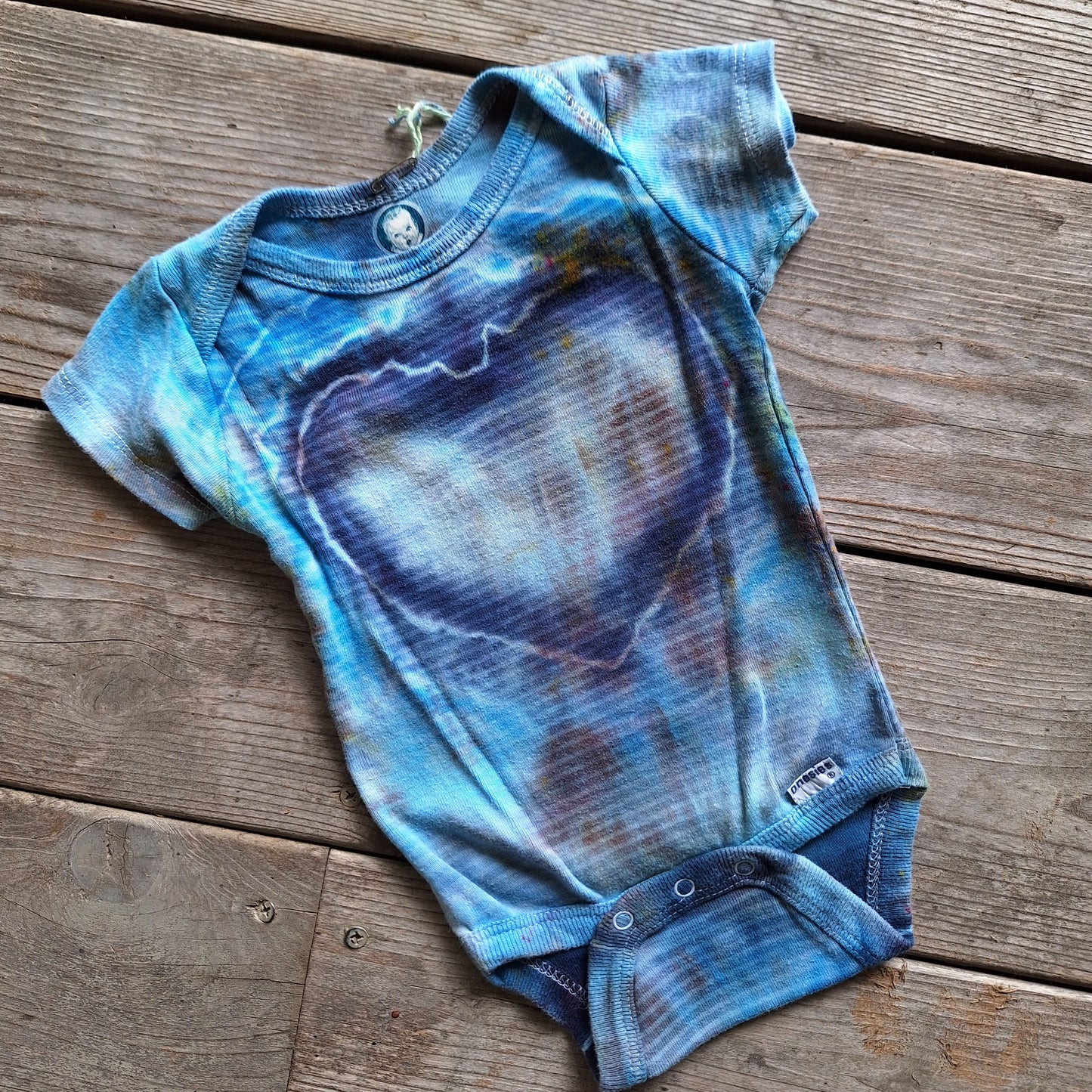 Blue tie-dye baby onesie on a wooden surface