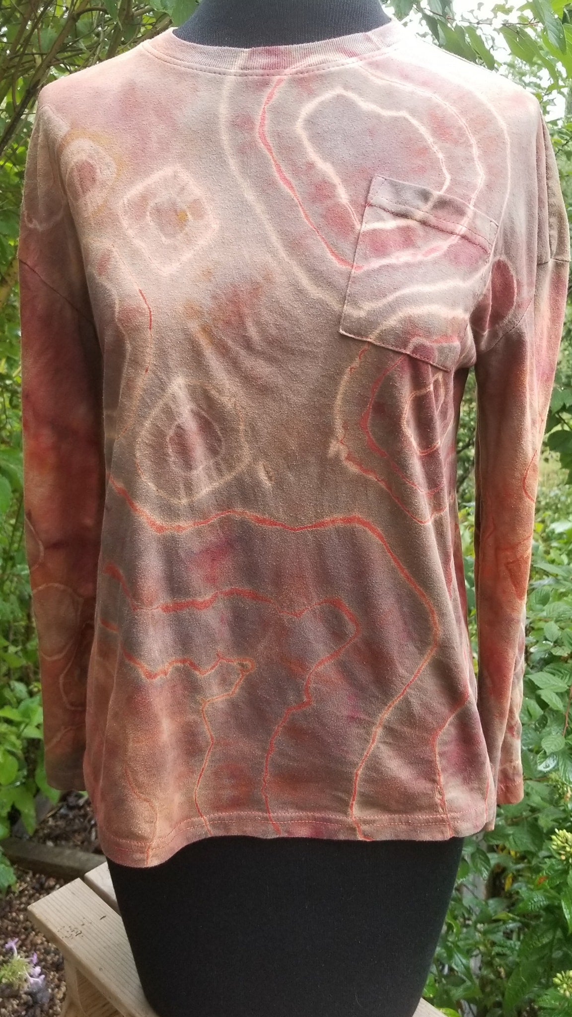Long-sleeve shirt with abstract tie dye design on a mannequin against a natural background