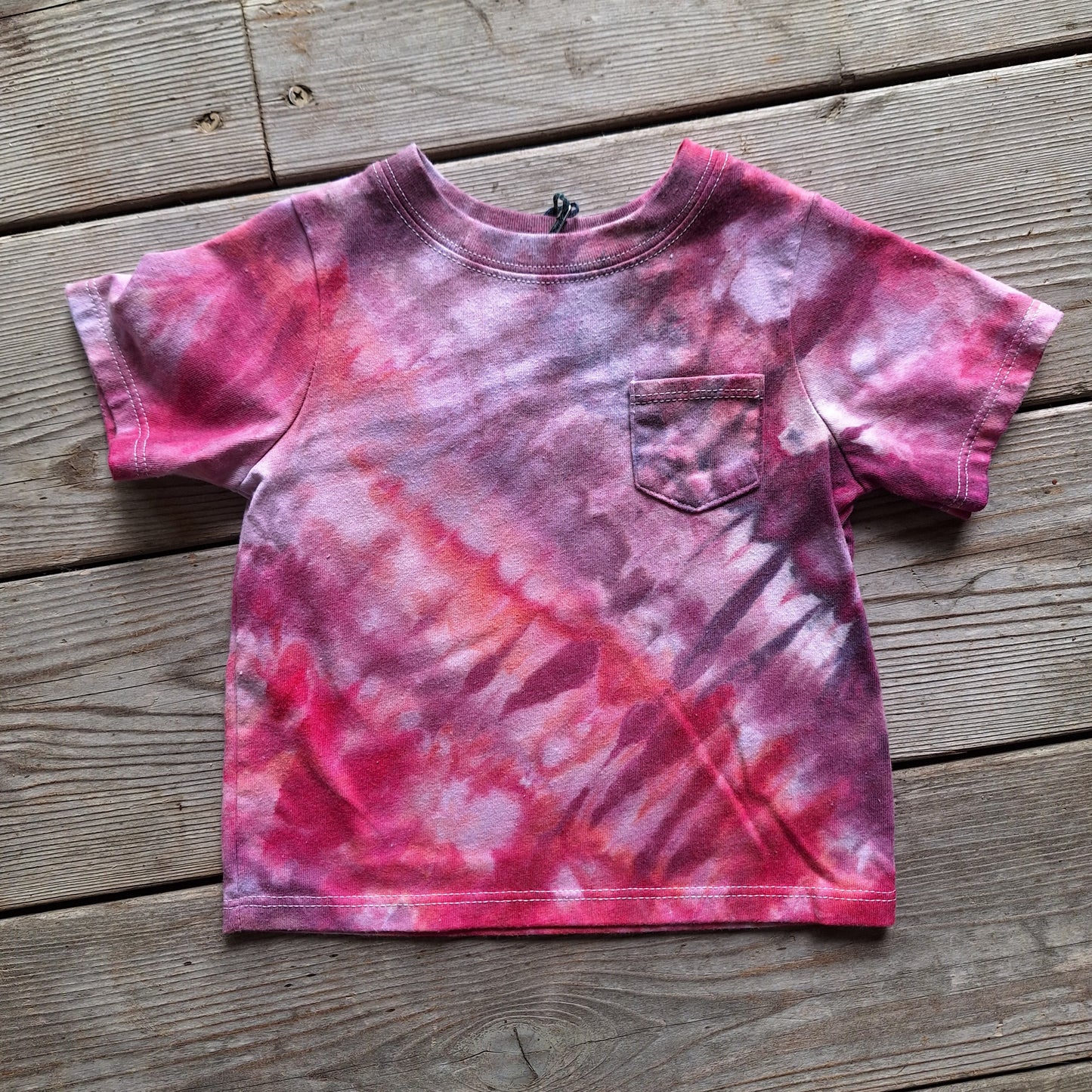 Pink and purple tie-dye t-shirt on a wooden surface