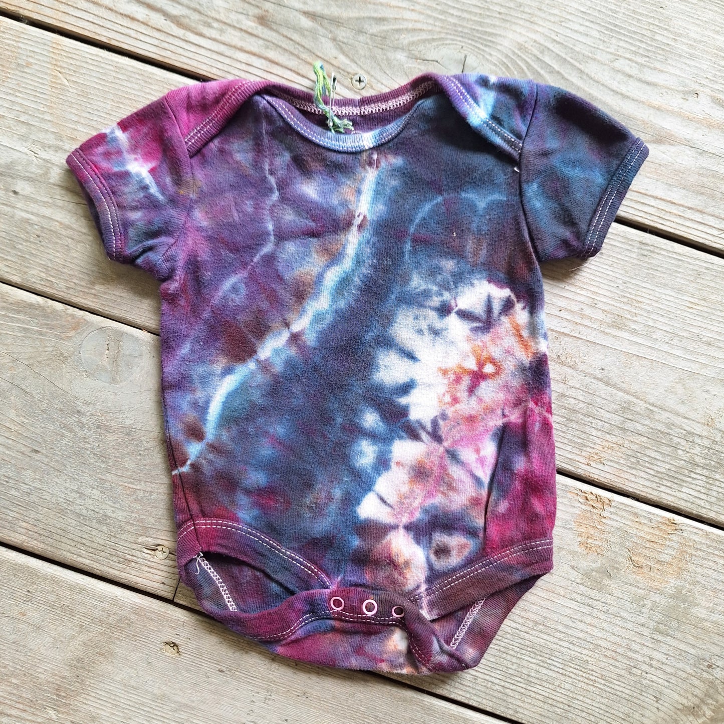 Tie-dye baby onesie on a wooden surface
