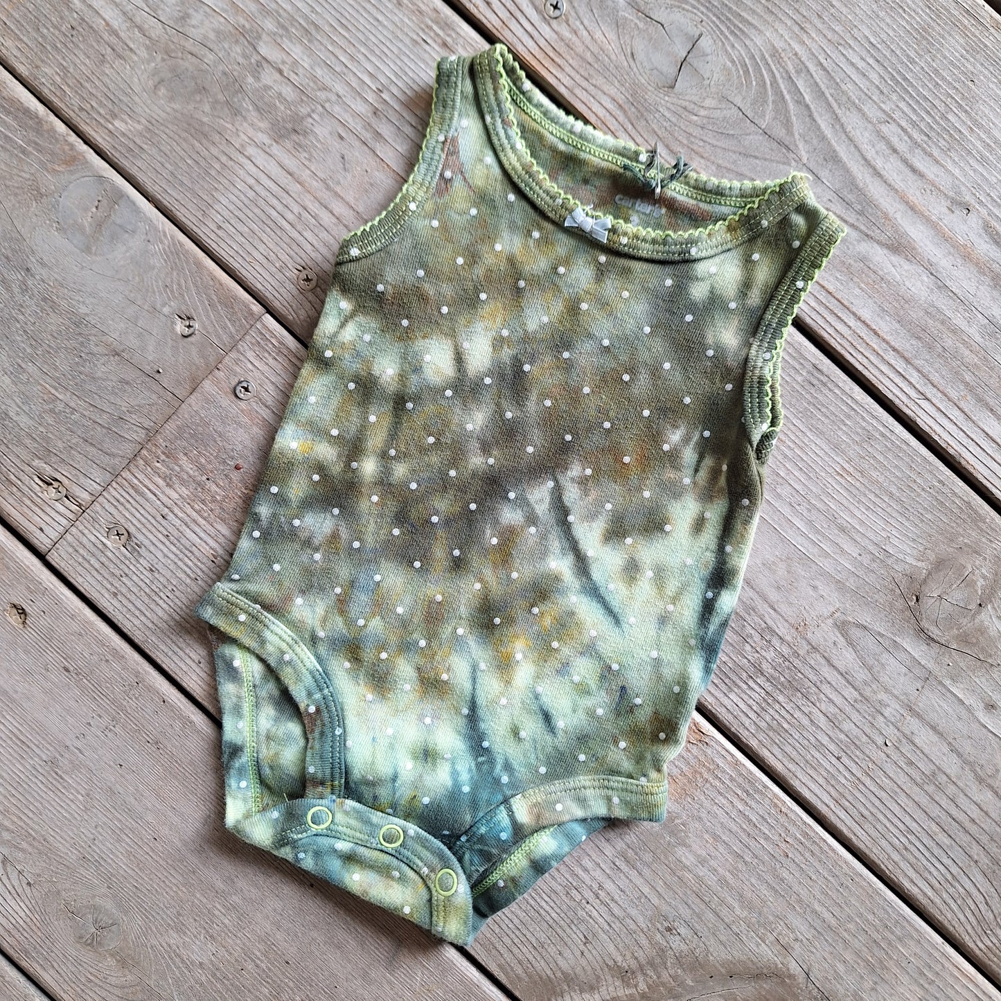 Baby onesie with tie-dye pattern on a wooden surface