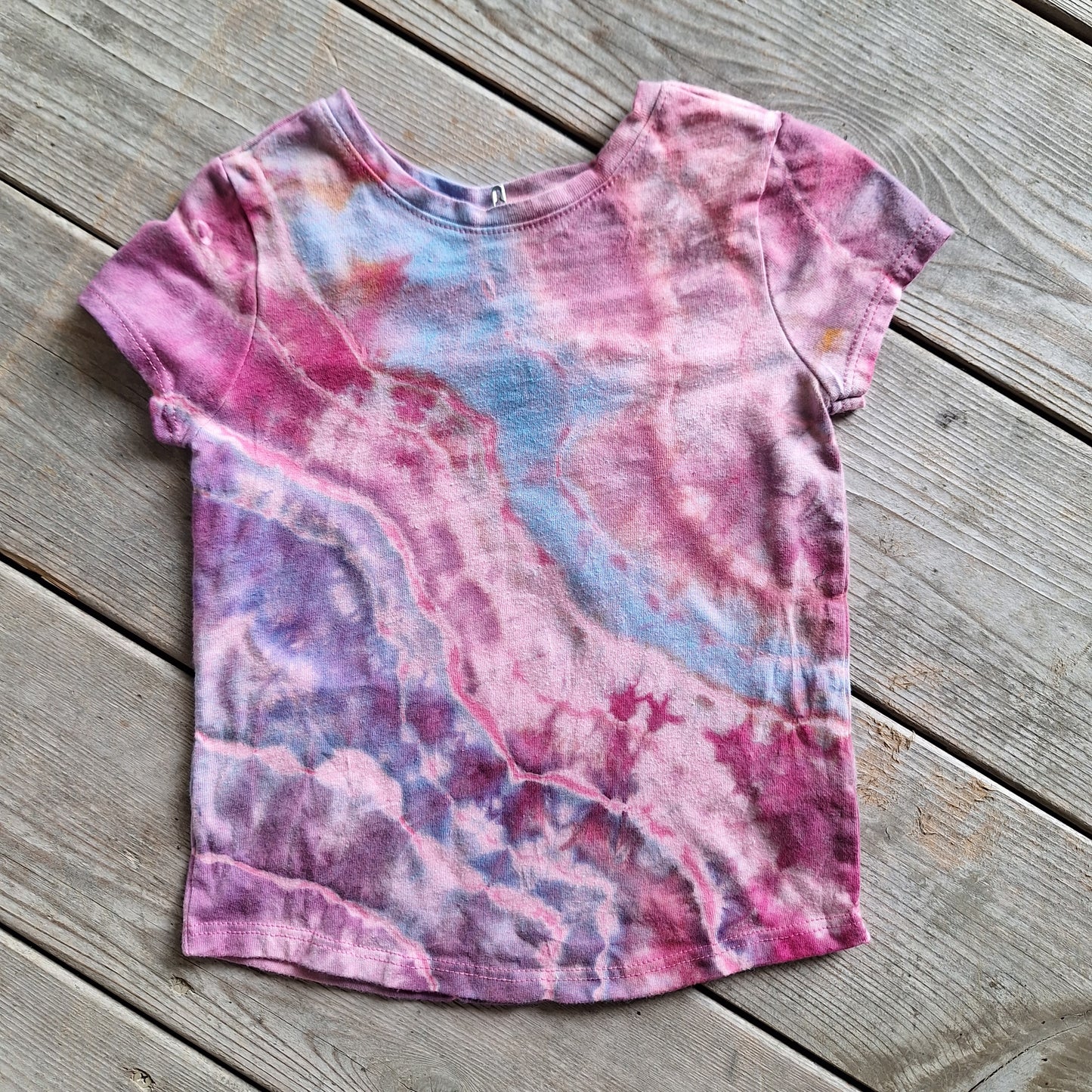 Tie-dye t-shirt with pink and blue patterns on a wooden surface