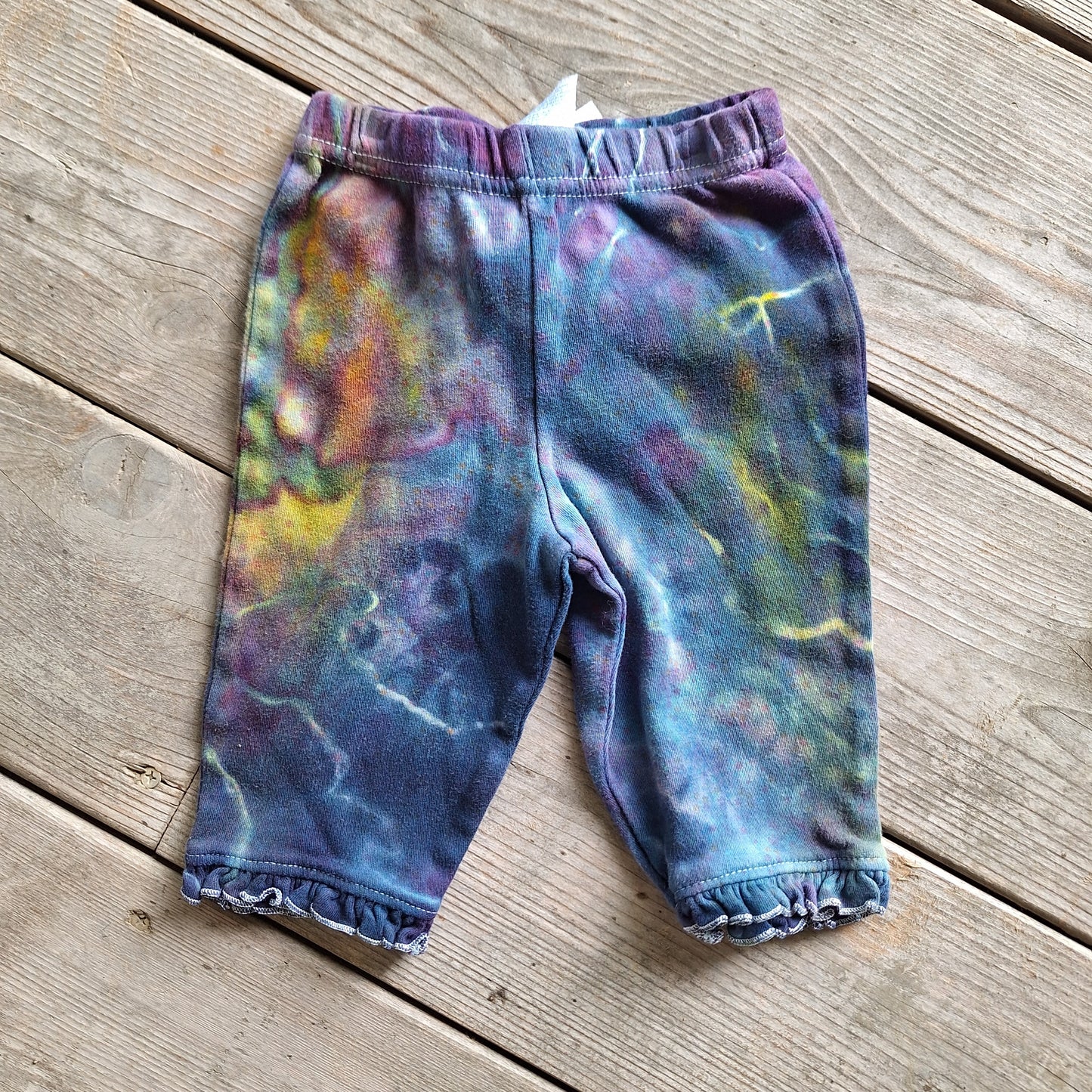 Colorful tie-dye baby pants on a wooden surface