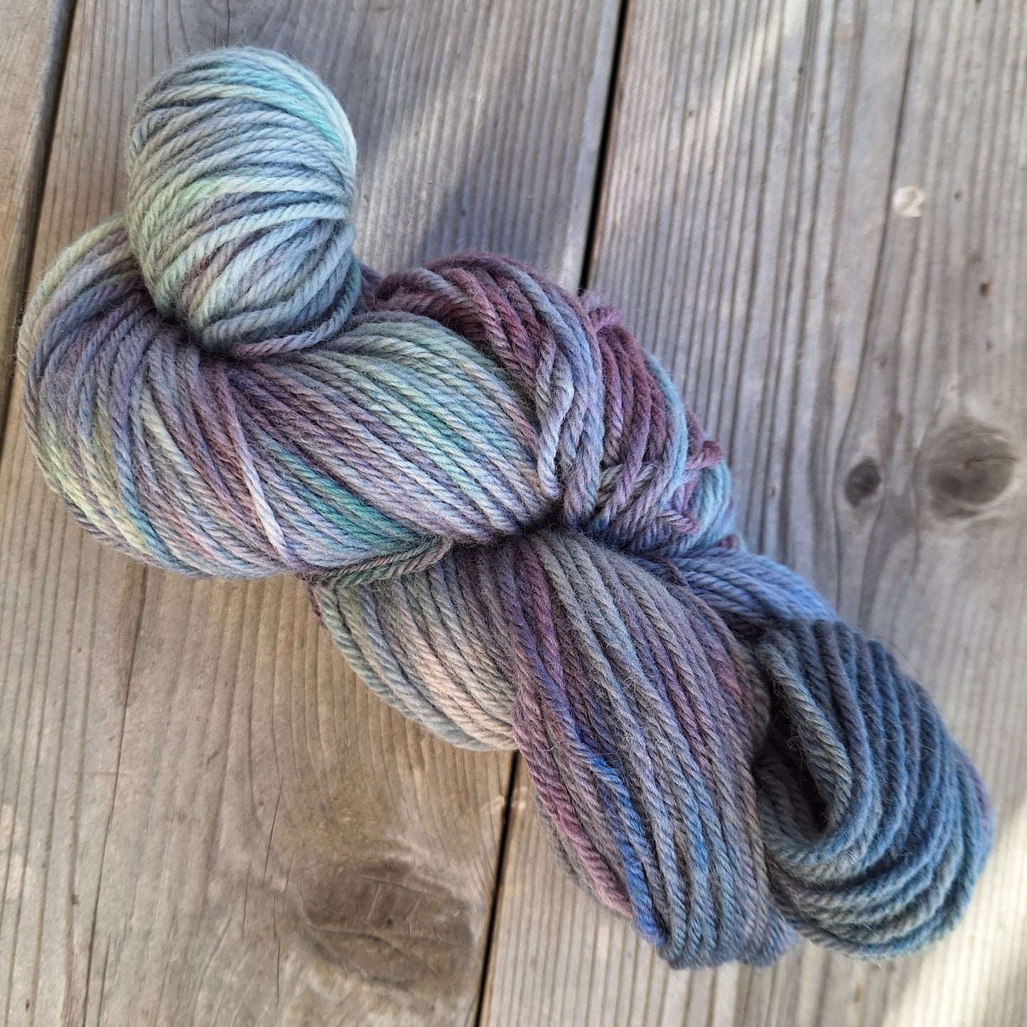 Multicolored skein of hand dyed yarn on a wooden surface