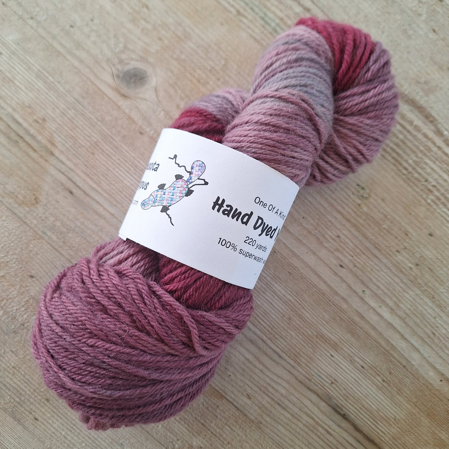 Skein of pink yarn with a label on a wooden surface