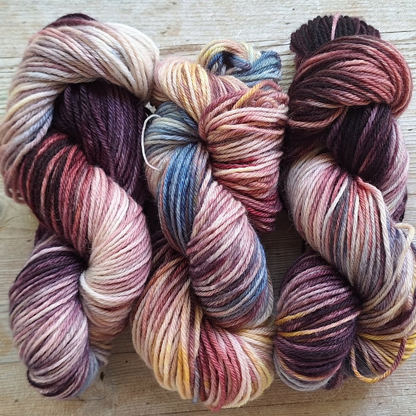 Three skeins of multicolored yarn on a wooden surface