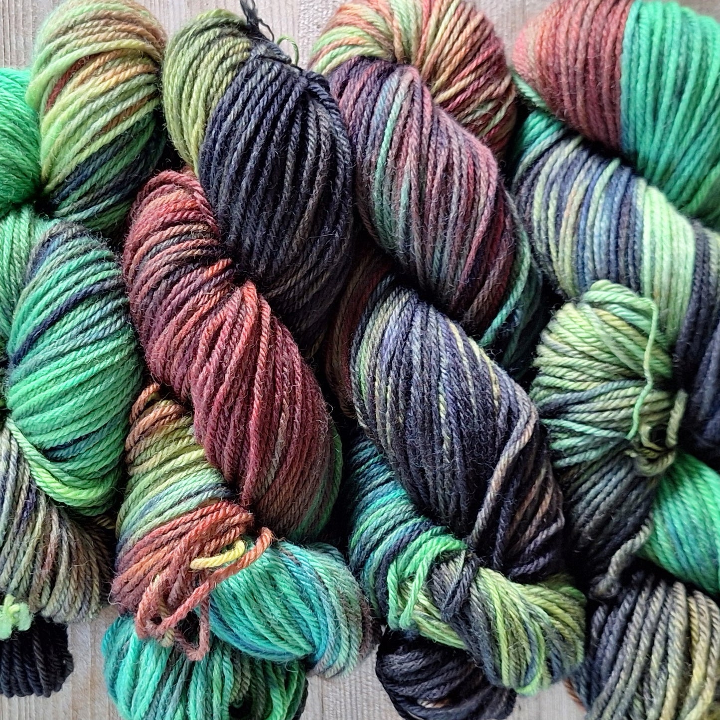 Colorful skeins of worsted weight wool yarn in Rich Multi green/ navy/ rust / chartreuse