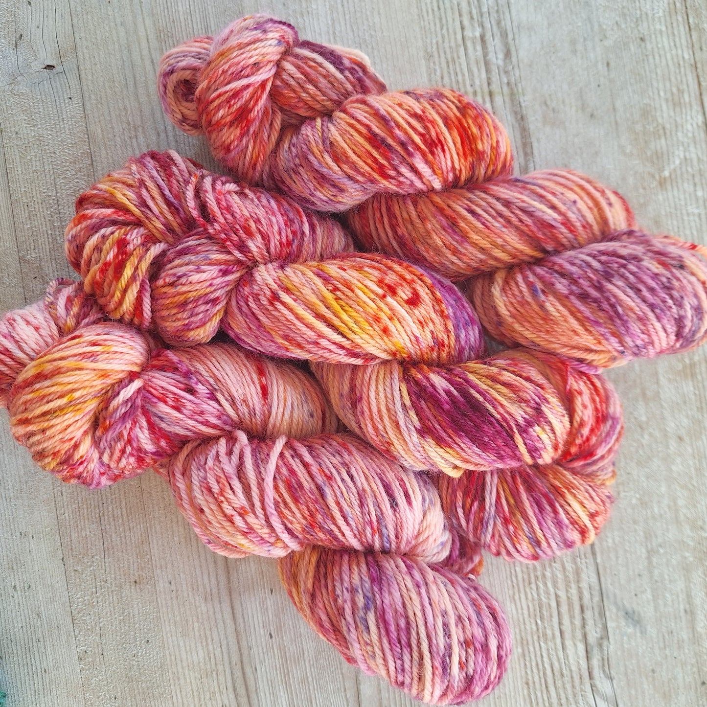 Multicolored speckled yarn skeins on a wooden surface