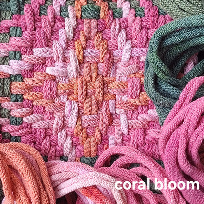 Close-up of woven potholder with pink, salmon, and green loops and 'coral bloom' text.