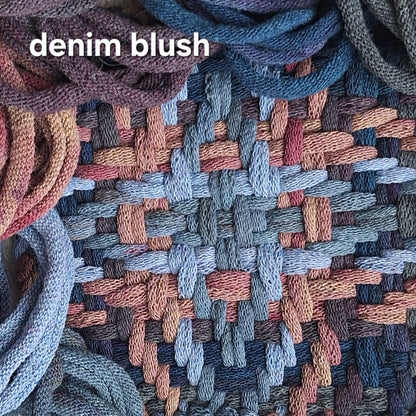 A close-up of a woven textile with a basketweave pattern in dusty blue, slate gray, mauve, blush pink, and taupe. The words 'denim blush' appear in white text at the top left.