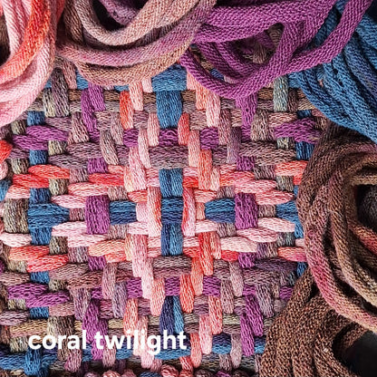 Close-up of woven potholder with 'coral twilight' label surrounded by cotton loops