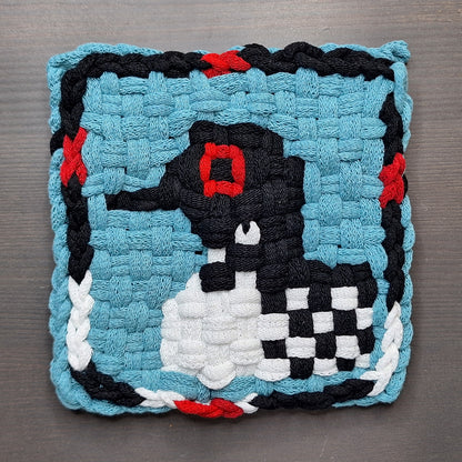 Woven potholder with a loon on a blue background