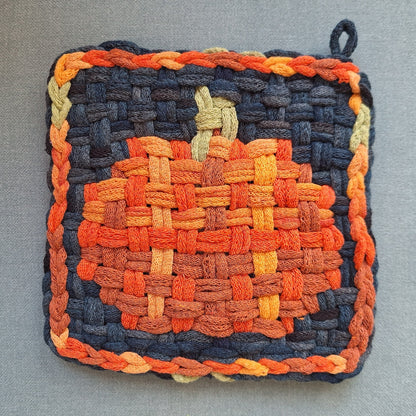 Woven potholder with pumpkin design on a gray background
