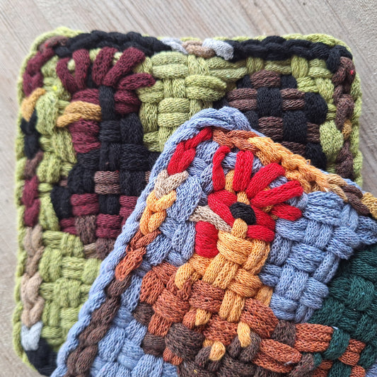 Two colorful woven trivets on a wooden surface