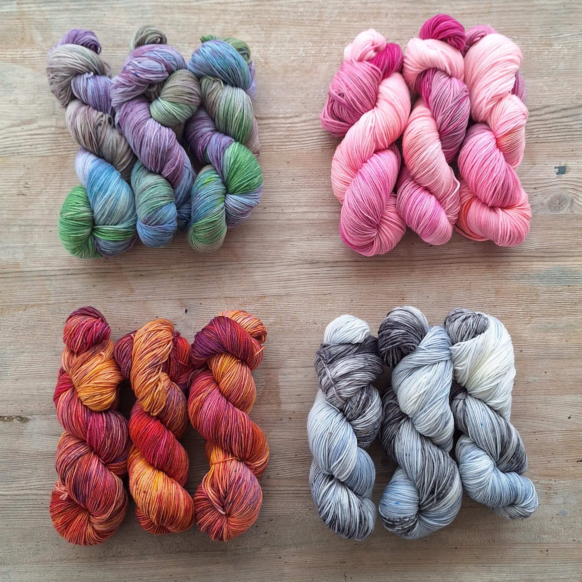 Four skeins of colorful yarn on a wooden surface
