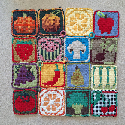 Colorful woven potholers with fruit and vegetable patterns on a gray background