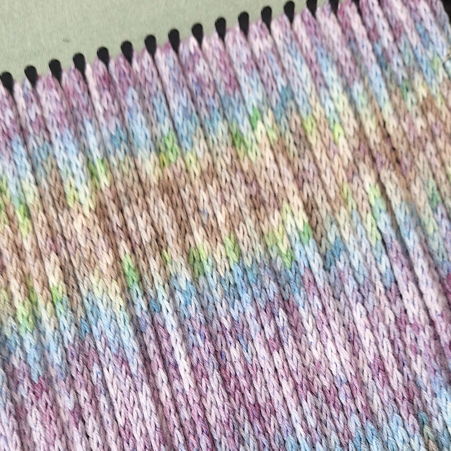 Close-up of a potholder loom warped with colorful i-cord