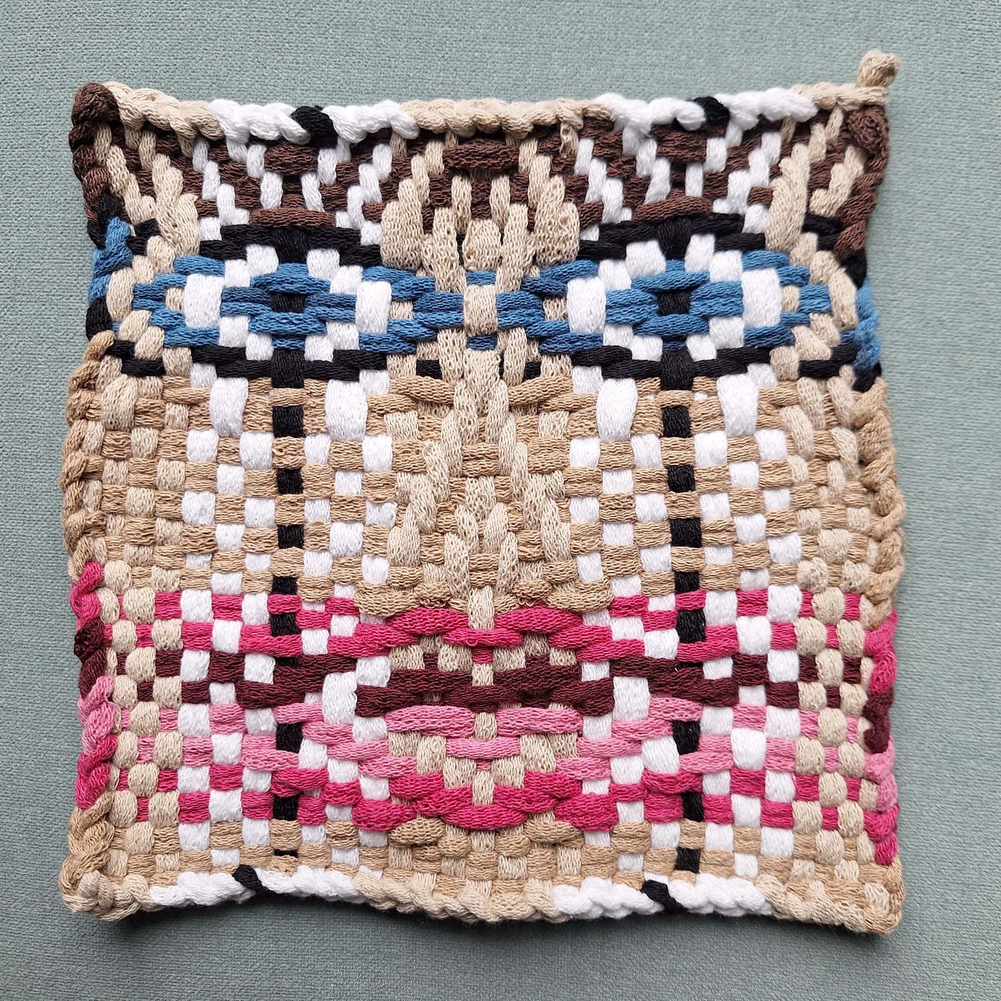 Woven potholder with geometric face pattern on a gray background
