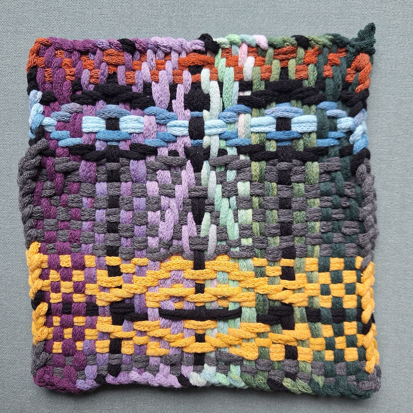Woven textile with multicolor face pattern on a gray background