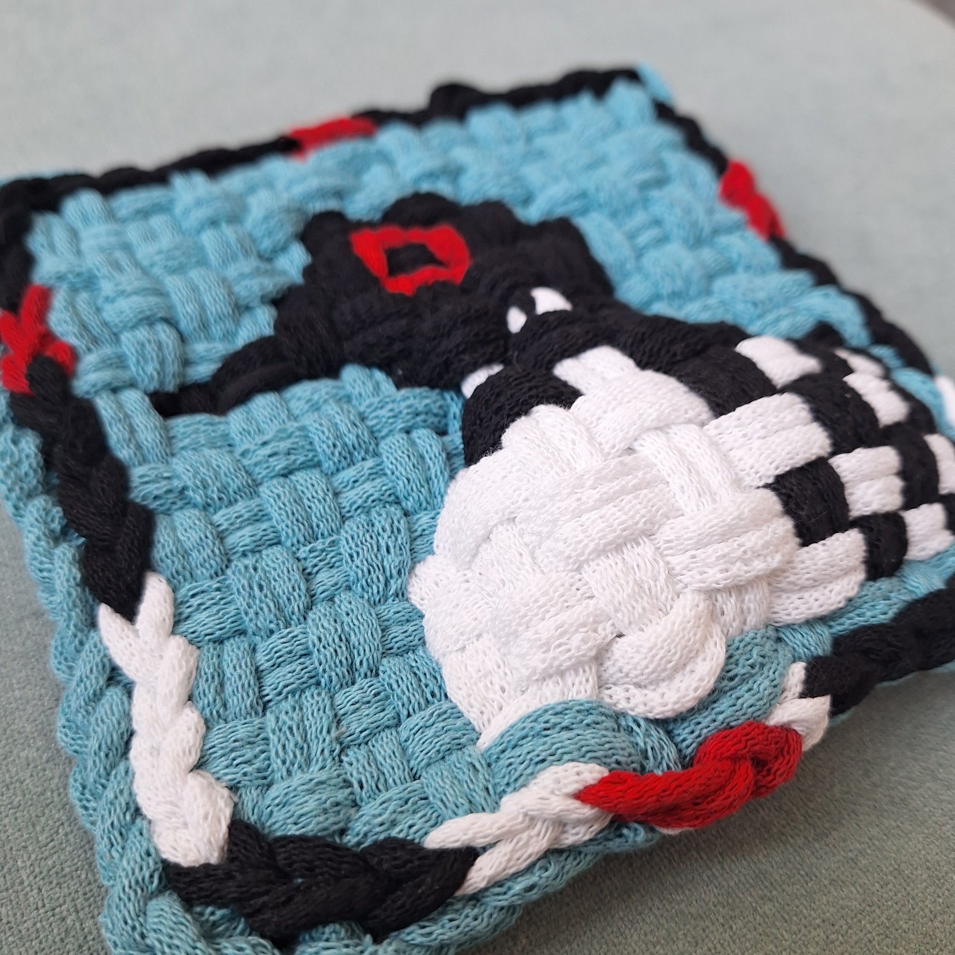 woven potholder with a loon pattern on a gray surface