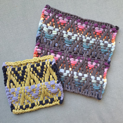 Two woven potholders with colorful patterns on a gray surface