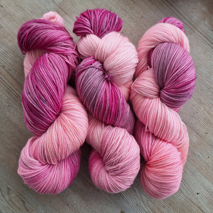 Pink and purple yarn skeins on a wooden surface
