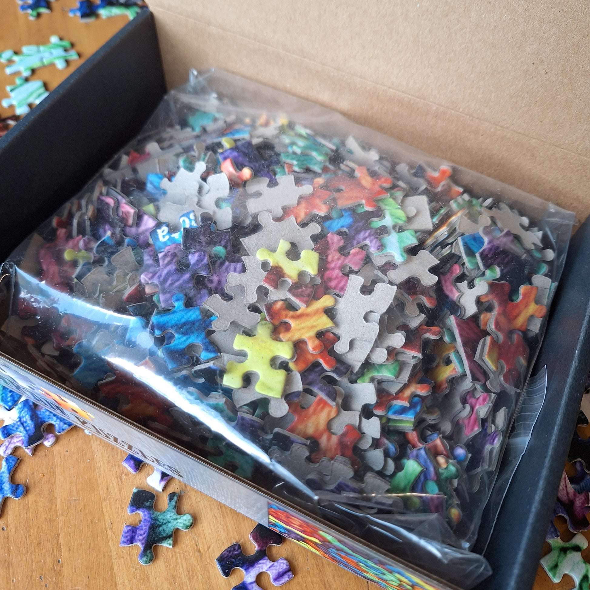 Jigsaw puzzle pieces in a clear plastic bag with a partially completed puzzle on a wooden surface.