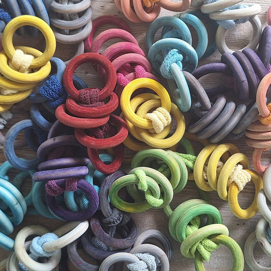 Colorful assortment of hand dyed potholder rings on a wooden surface
