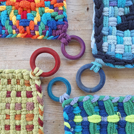 Colorful woven potholders with red purple and blue rings on a wooden surface