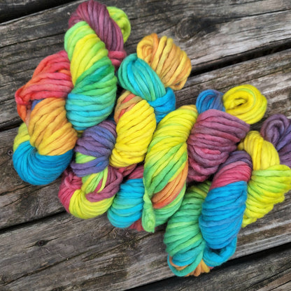 Colorful skeins of pencil roving yarn on a wooden surface