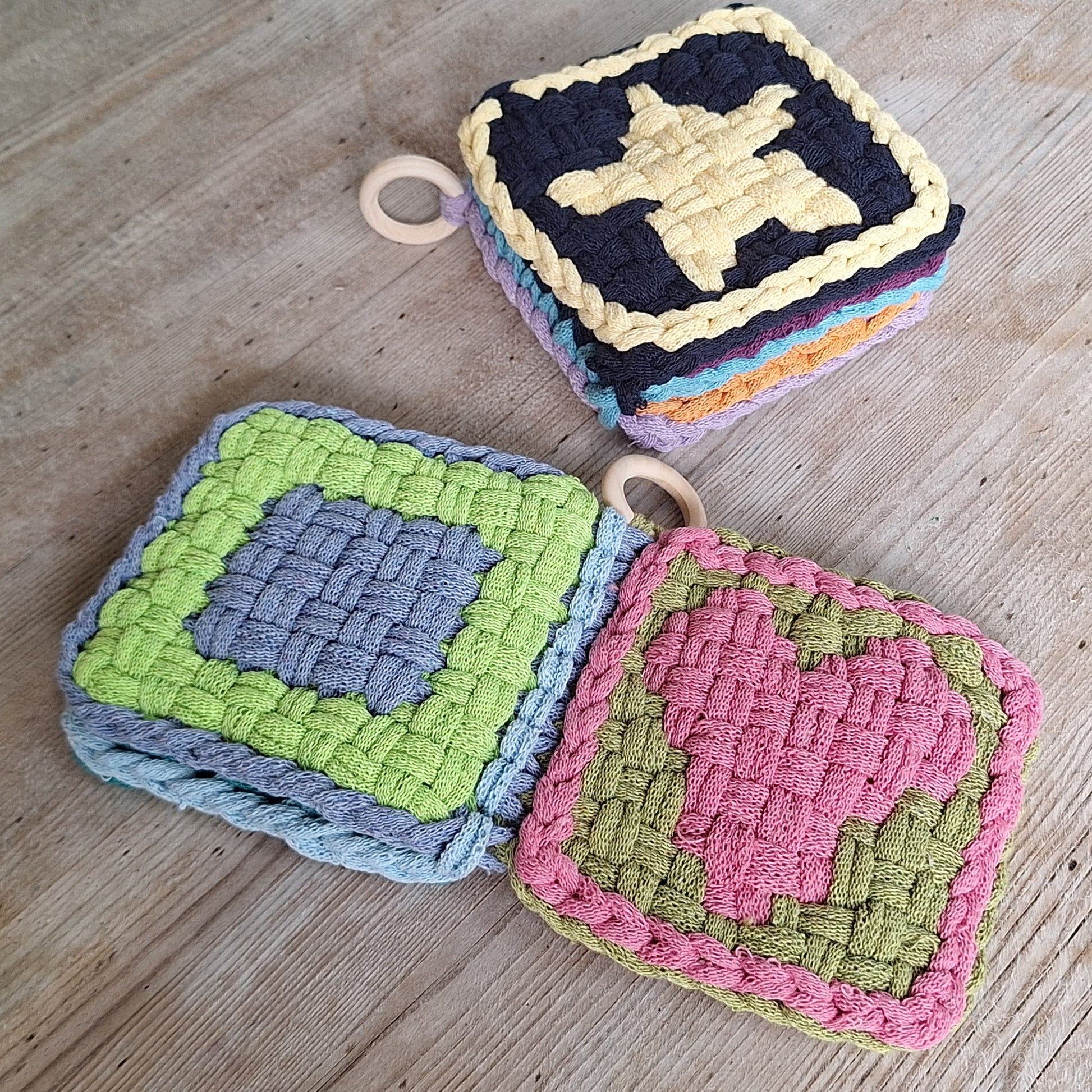 two samples of greta's shapes potholder book on a wood table