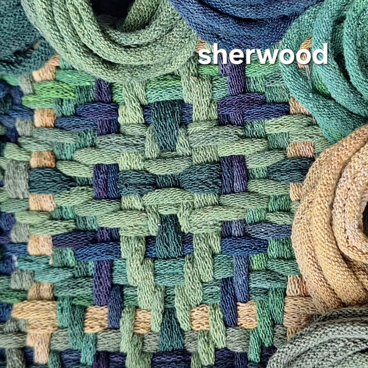 A close-up of a woven textile made from cotton loops in muted green, teal, navy, gold, and gray green, with the word 'sherwood' overlaid near the top.