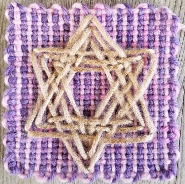 Star shaped embroidery on a pink and purple woven square