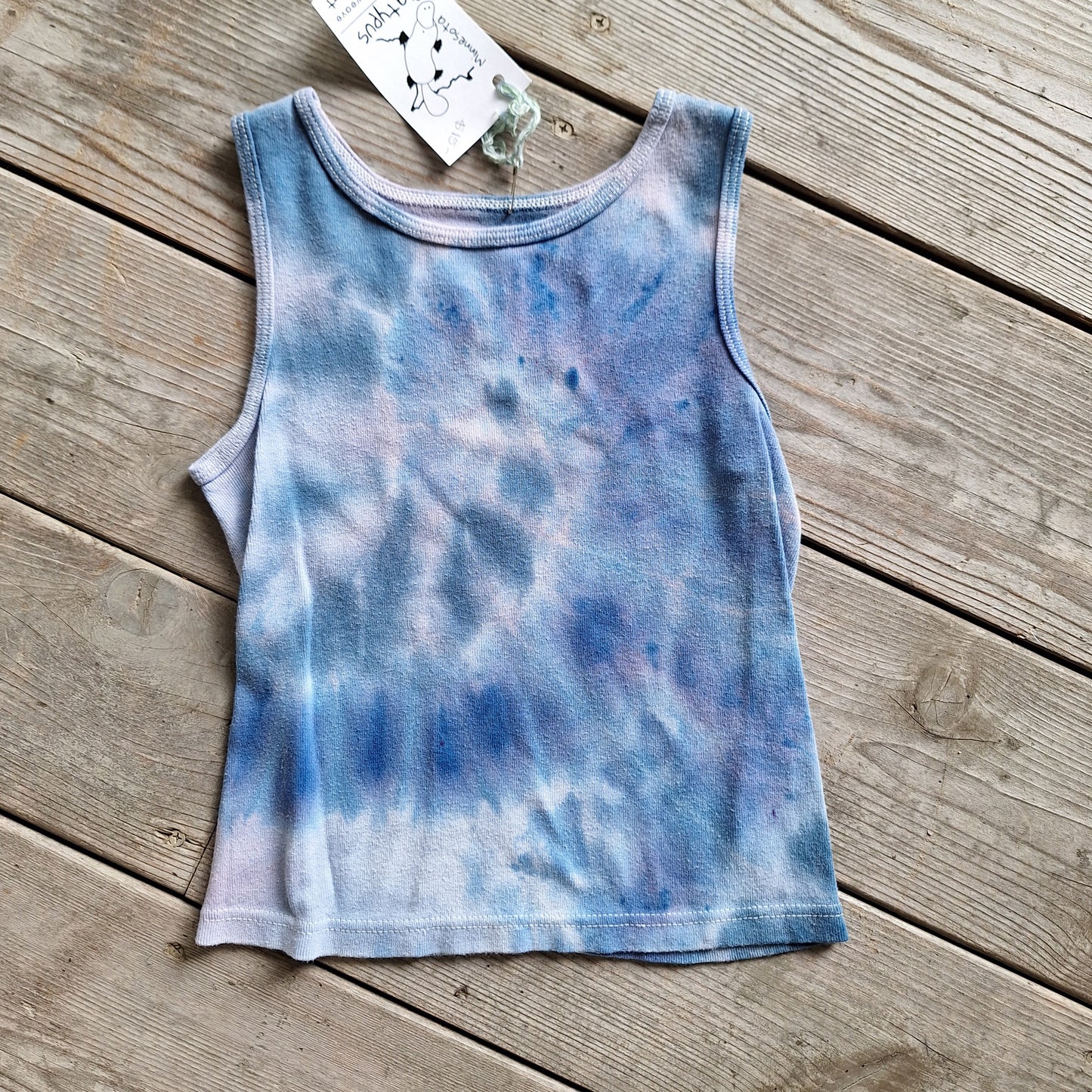 Tie-dye tank top on a wooden surface with a tag attached