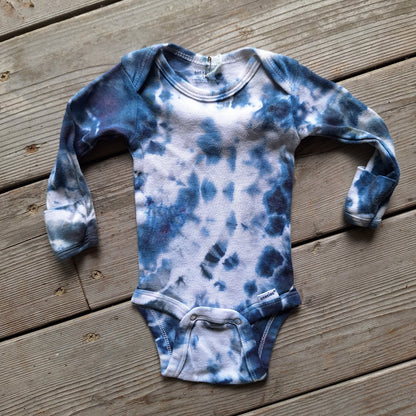 Blue and white tie-dye baby onesie on a wooden surface