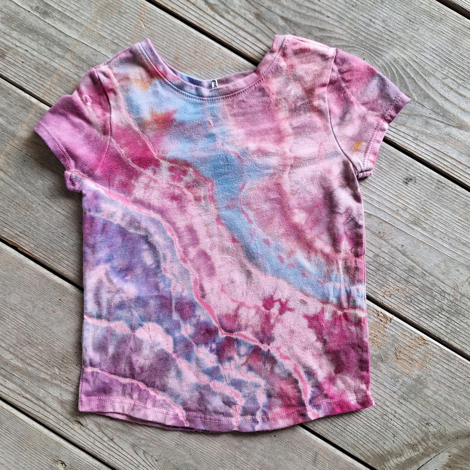 Tie-dye t-shirt with pink and blue patterns on a wooden surface