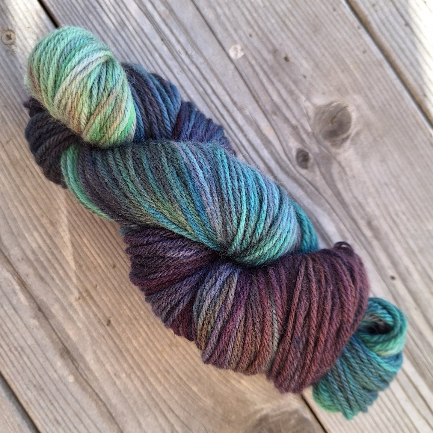 Multicolored skein of hand dyed yarn on a wooden surface
