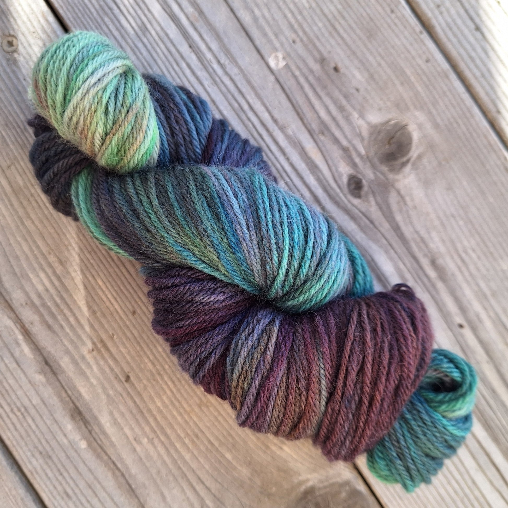 Multicolored skein of hand dyed yarn on a wooden surface