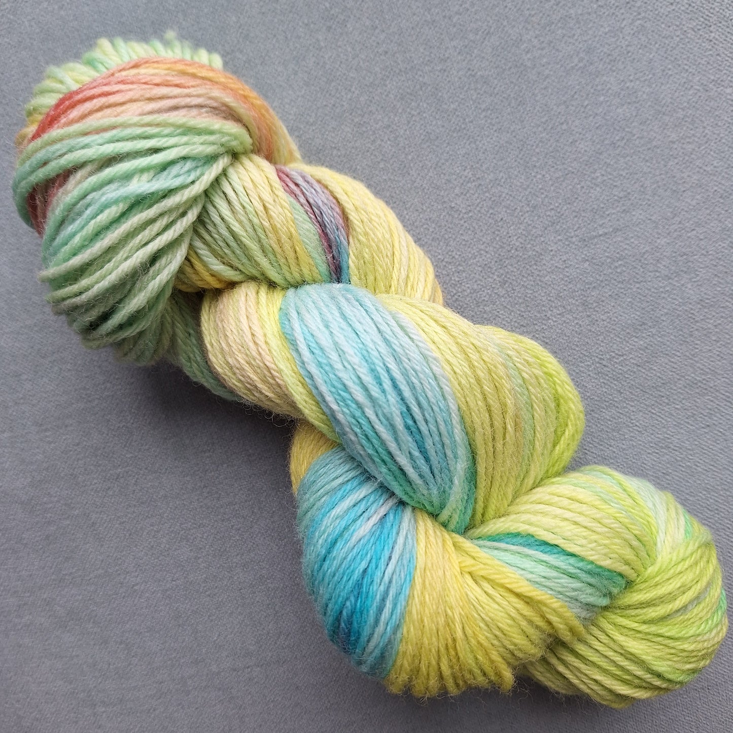 Multicolored skein of hand dyed yarn on a gray background